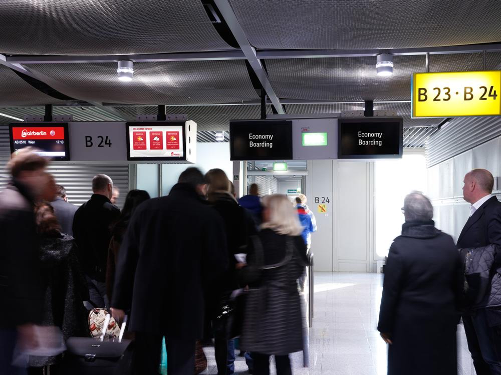 DUS Ad Gate Reisende auf dem Weg nach Wien vor den Screens (Foto: Flughafen Düsseldorf GmbH)