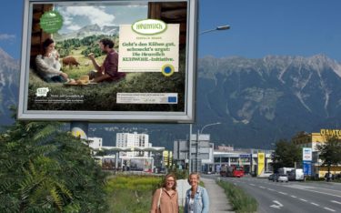 Christiane Mösl (l), Geschäftsführung ARGE Heumilch Österreich und Brigitte Huber, Account Manager Epamedia Tirol vor einem Poster der Kuhwohl-Kampagne (Foto: Epamedia)