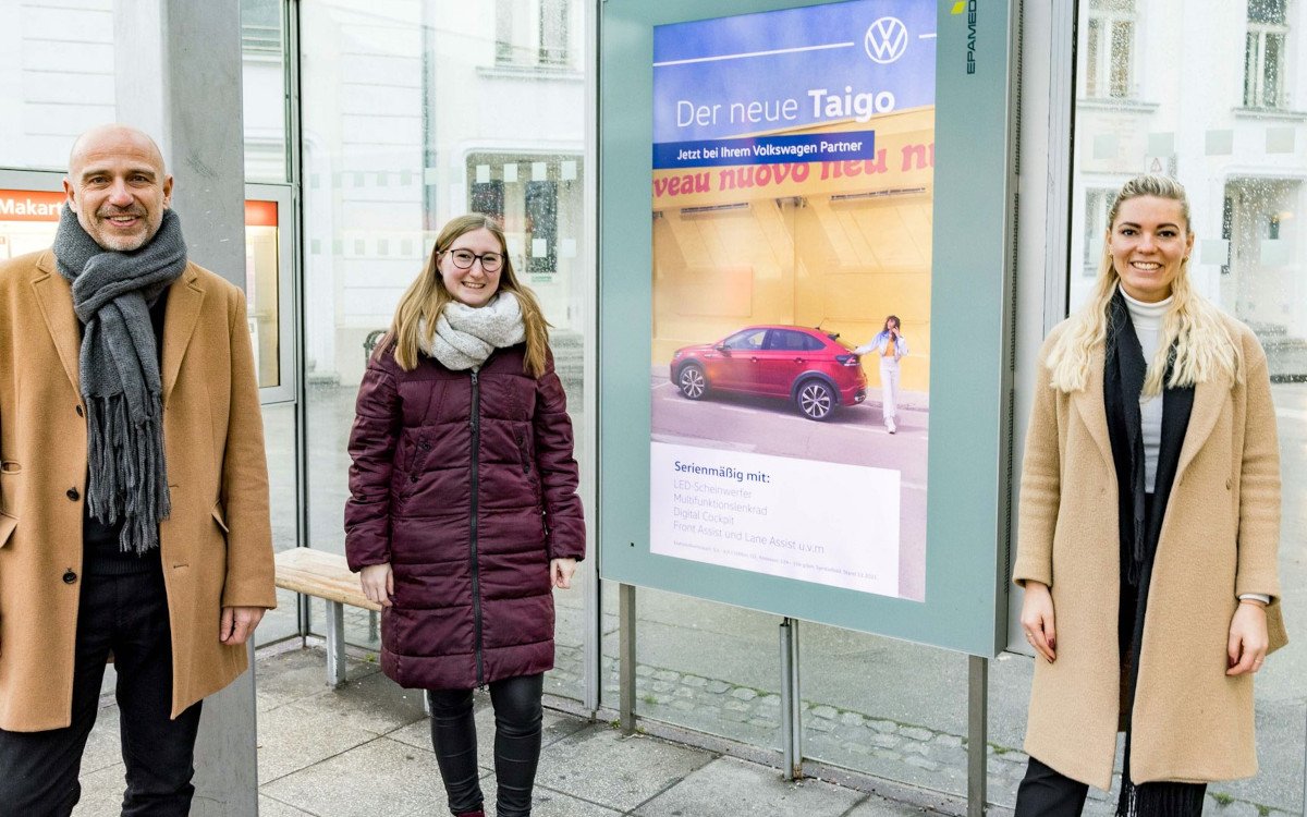 Von links: Thomas Frauenschuh (Epamedia), Sonja Toplak (Mediaplanung PMC) und Alina Schulz (Marketing VW Österreich) vor einem DooH-Screen mit dem VW Taigo (Foto: EPAMEDIA)