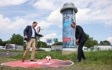 Bereit für die EM: Stephan Keller, Oberbürgermeister von Düsseldorf (links), und Stephan Schneider, Leiter Politische Kommunikation NRW bei Vodafone, wagen einen Kick vor der Mobilfunk-Litfaßsäule. (Foto: Vodafone)