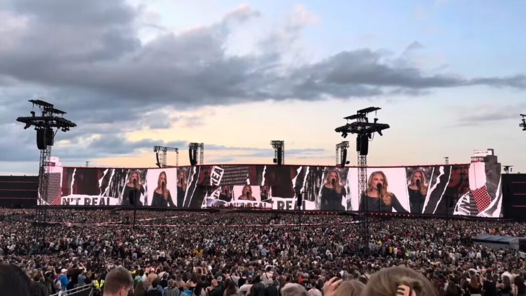 Während Adele auf einem Podium singt, läuft auf dem Megascreen im Hintergrund eine maßgeschneiderte Videoshow ab. (Foto: Screenshot/ In Concert)