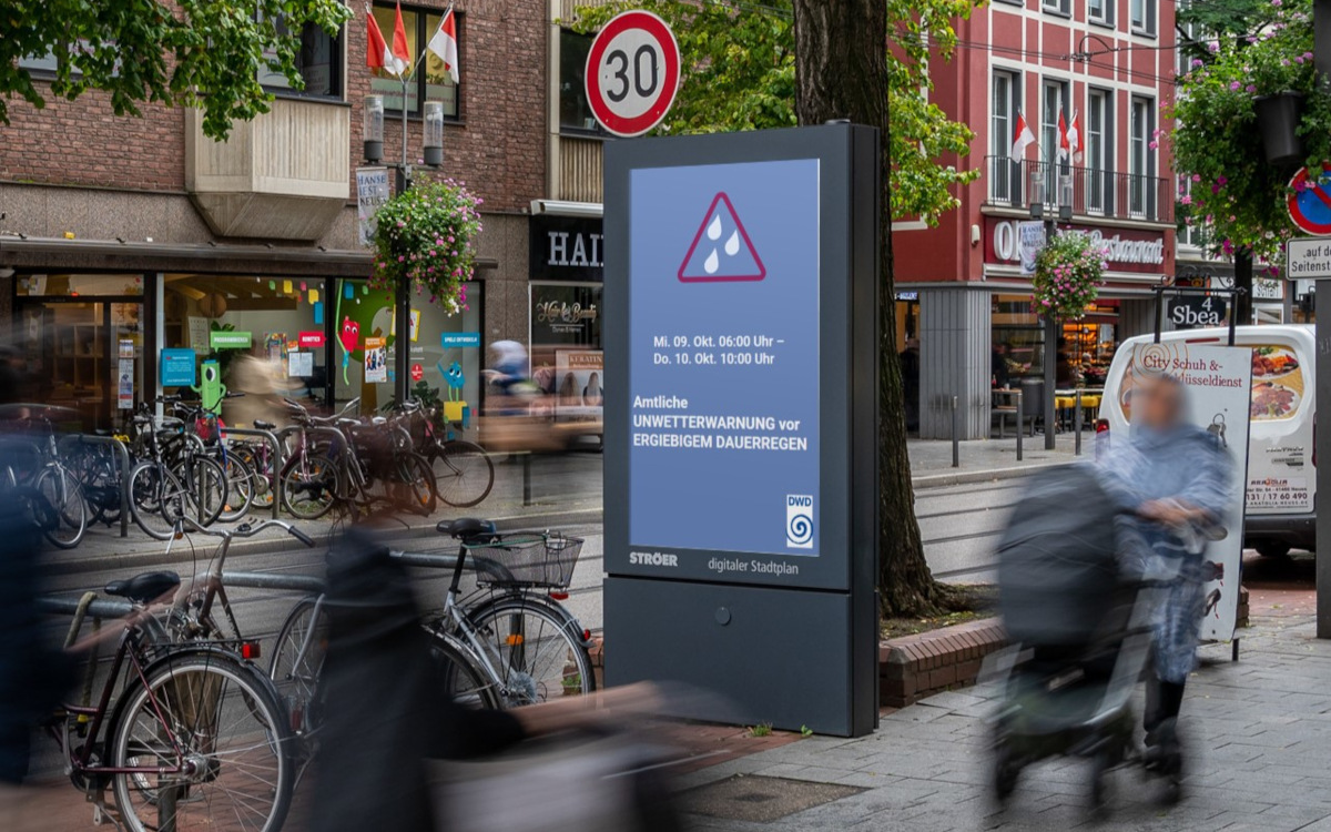 Amtliche Unwetterwarnungen können viele Städte inzwischen durch Zugang zu DooH-Netzwerken auf öffentlichen Screens ausspielen. (Bildmontage: Ströer)