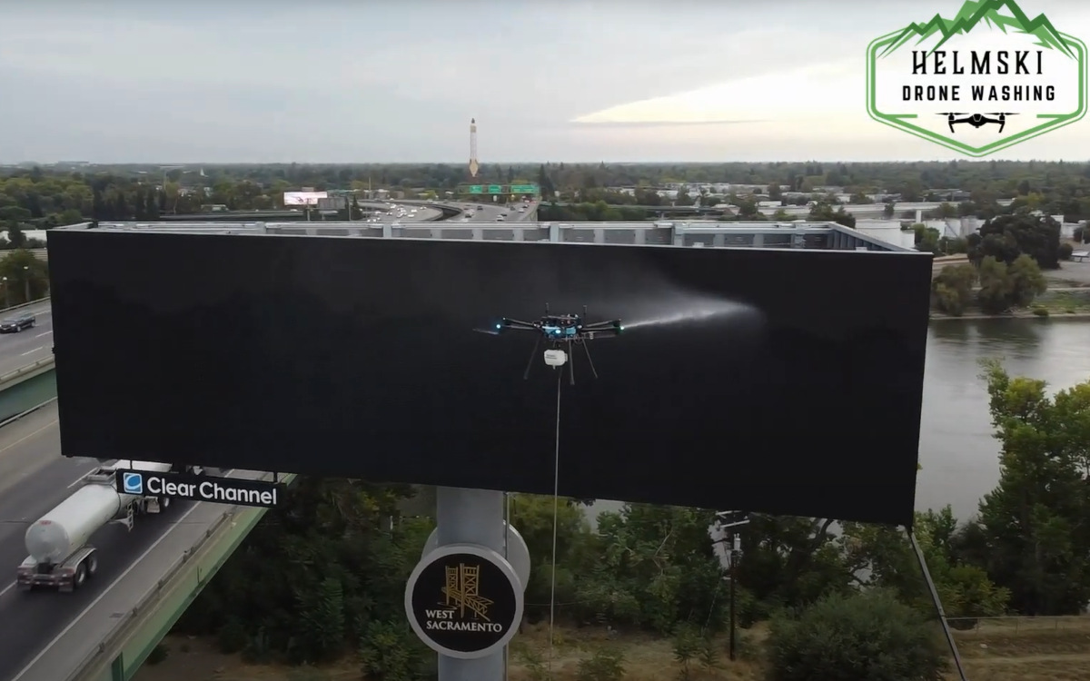 Eine Drohne von Helmski reinigt ein Clear-Channel-Billboard. (Foto: Helmski Pressure Washing/Screenshot)