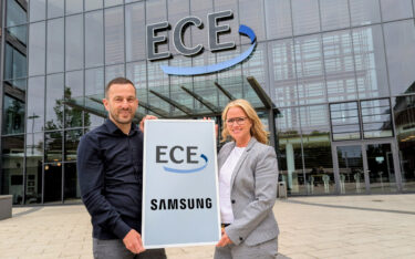 Bettina Roderhoff, Head of B2B Sales LCD-Signage bei Samsung Electronics Deutschland, übergibt das E-Paper-Display an Marcus Schwartz, Lead New Business bei ECE Marketplaces (Bild: invidis)